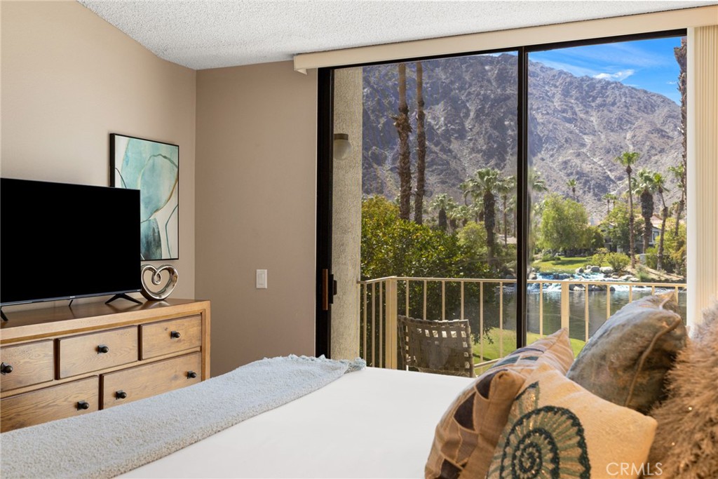 79822 Olympia Fields La Quinta, CA 92253 - Photo 19 of 48 a bedroom with a bed and a flat tv screen next to a window