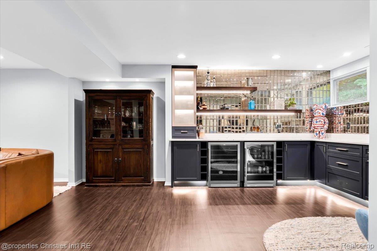 3939 Charing Cross Road Bloomfield Hills, MI 48304 - Photo 30 of 33 Built-in bar featuring two beverage refrigerators, dark cabinetry, and a mirrored tile backsplash
