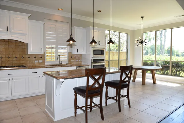 a kitchen with stainless steel appliances granite countertop table chairs and a view of living room