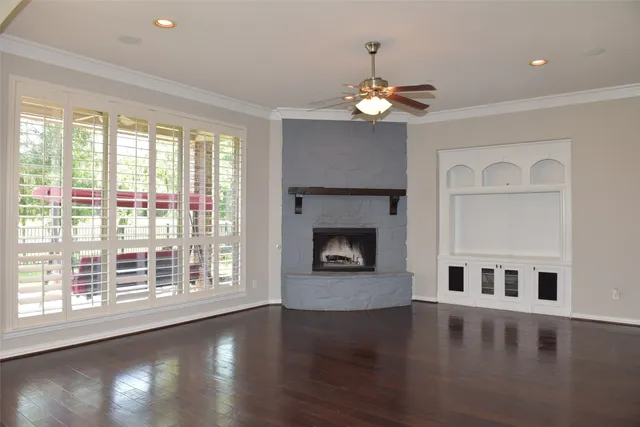 a view of an empty room with wooden floor fireplace and a window