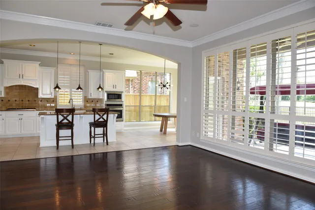 a dining room with wooden floor a chandelier a glass table and chairs
