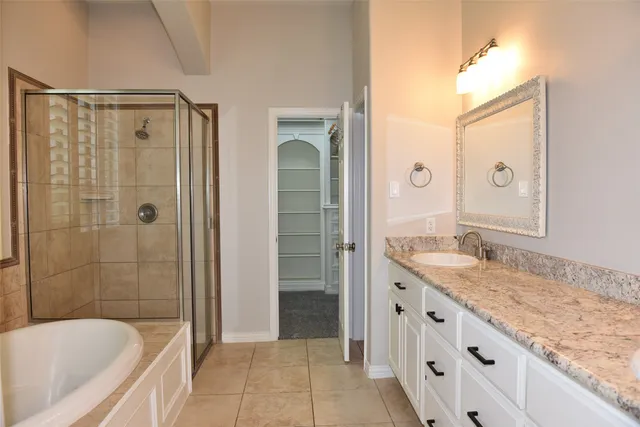 a bathroom with a granite countertop sink a mirror a bathtub and shower