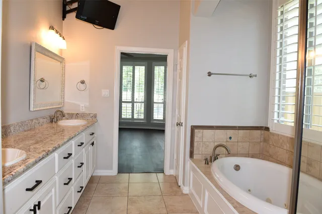 a bathroom with a granite countertop sink and mirror with bathtub