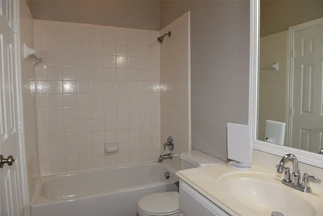 a bathroom with a bathtub shower sink vanity mirror and toilet