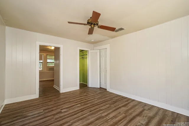 a view of empty room with wooden floor and ceiling fan