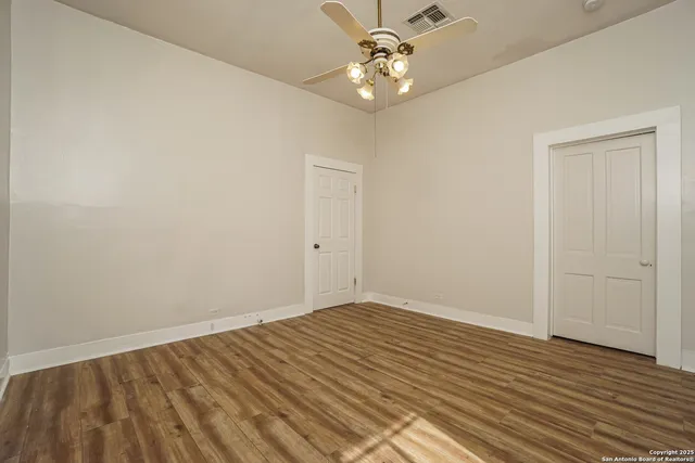 an empty room with wooden floor and ceiling fan