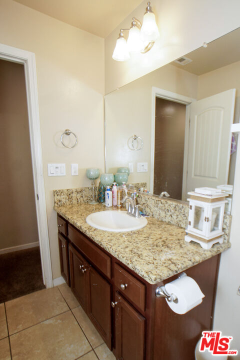 6014 Samuelson Street Bakersfield, CA 93313 - Photo 16 of 25 a bathroom with a granite countertop sink and a mirror