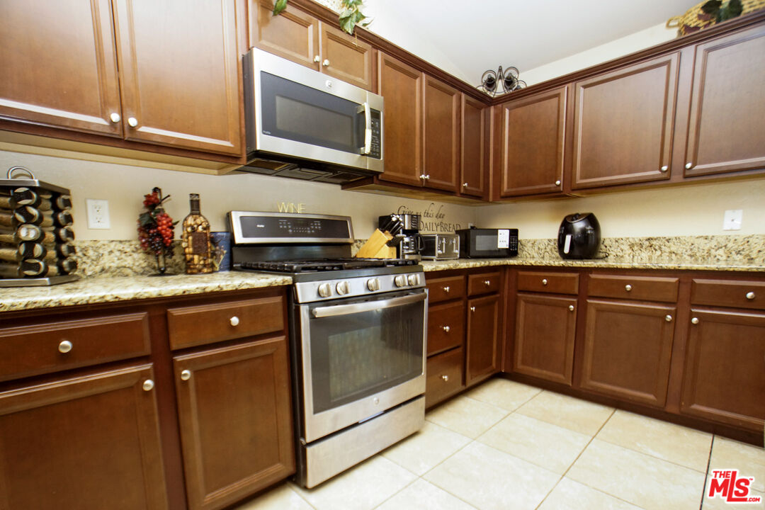 6014 Samuelson Street Bakersfield, CA 93313 - Photo 4 of 25 a kitchen with stainless steel appliances granite countertop a sink and cabinets