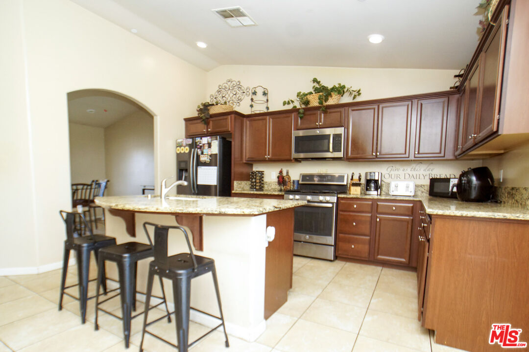 6014 Samuelson Street Bakersfield, CA 93313 - Photo 5 of 25 a kitchen with stainless steel appliances granite countertop a stove top oven a sink a dining table and chairs with wooden floor