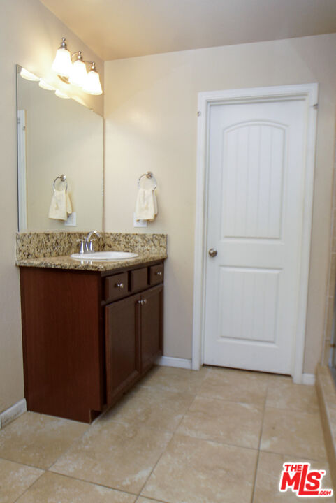 6014 Samuelson Street Bakersfield, CA 93313 - Photo 6 of 25 a bathroom with a granite countertop sink and a mirror