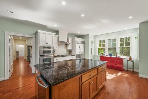 a kitchen with stainless steel appliances granite countertop a sink a stove and a wooden floors