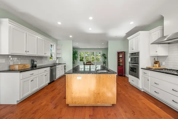 a large kitchen with stainless steel appliances granite countertop a lot of counter space and wooden floors