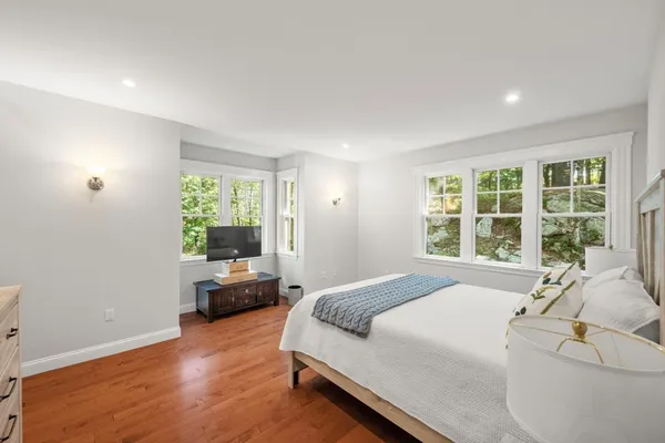 a spacious bedroom with a bed and wooden floor