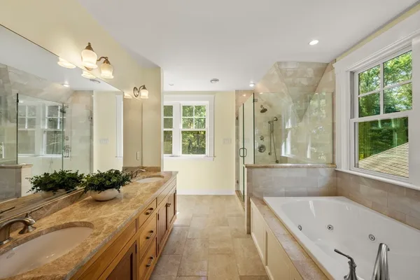 a bathroom with a granite countertop tub sink and mirror