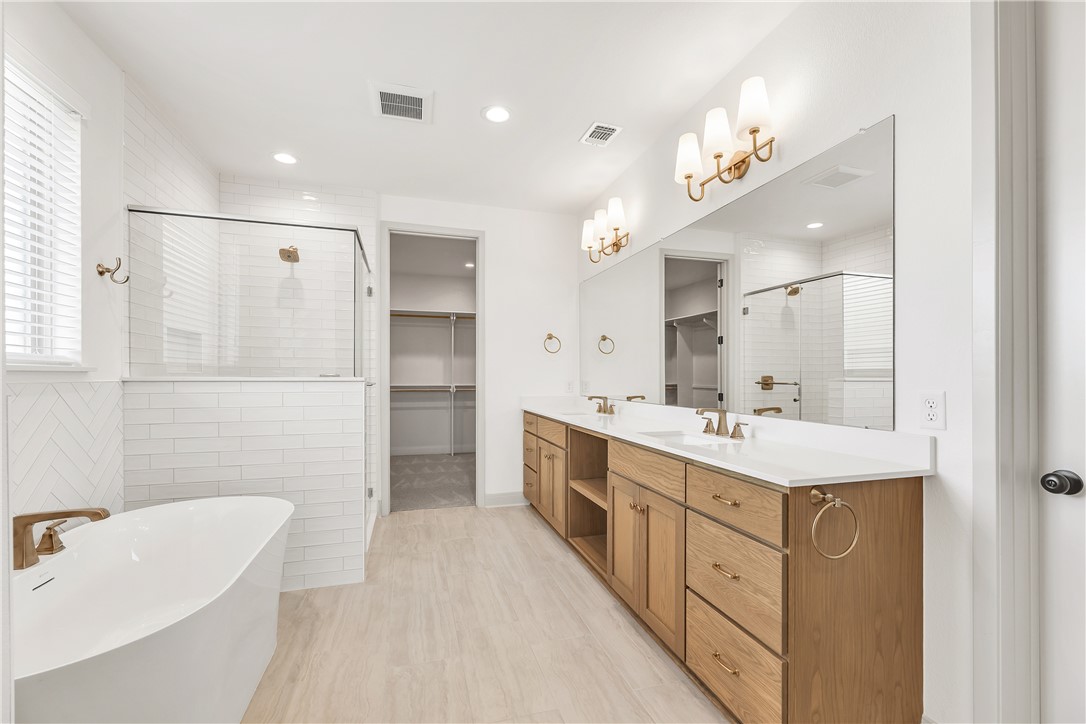 4007 Pacific Crest Way Bryan, TX 77802 - Photo 24 of 43 a large bathroom with a double vanity sink a large mirror a shower and bathtub