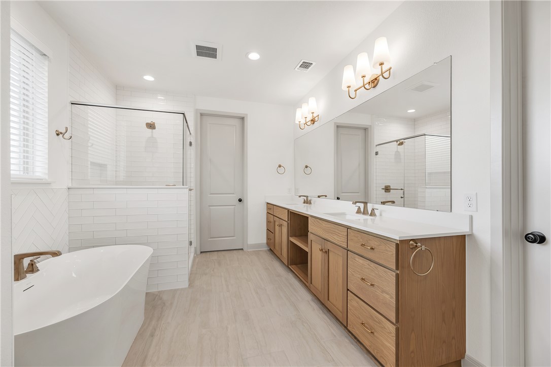 4007 Pacific Crest Way Bryan, TX 77802 - Photo 25 of 43 a spacious bathroom with a double vanity sink a mirror and a bathtub