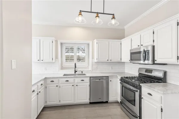 a kitchen with white cabinets stainless steel appliances and sink