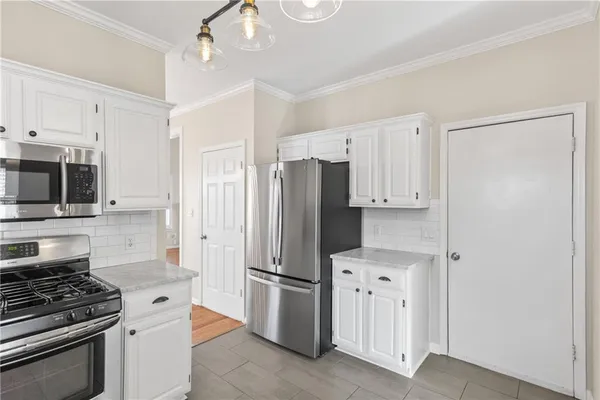 a kitchen with stainless steel appliances a refrigerator stove and white cabinets