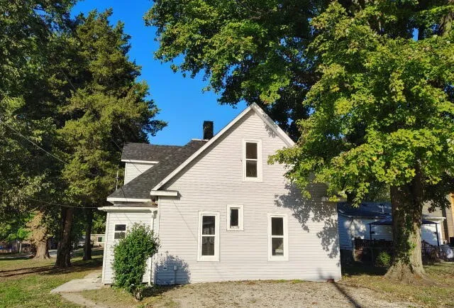 a view of a white house with a large tree