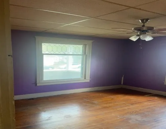 an empty room with a window and ceiling fan
