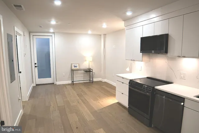 a kitchen with stainless steel appliances granite countertop a sink and a stove top oven with wooden floor