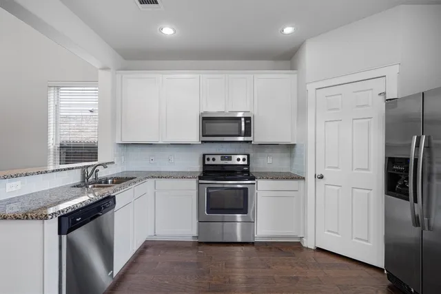 a kitchen with stainless steel appliances granite countertop a sink and a white cabinets