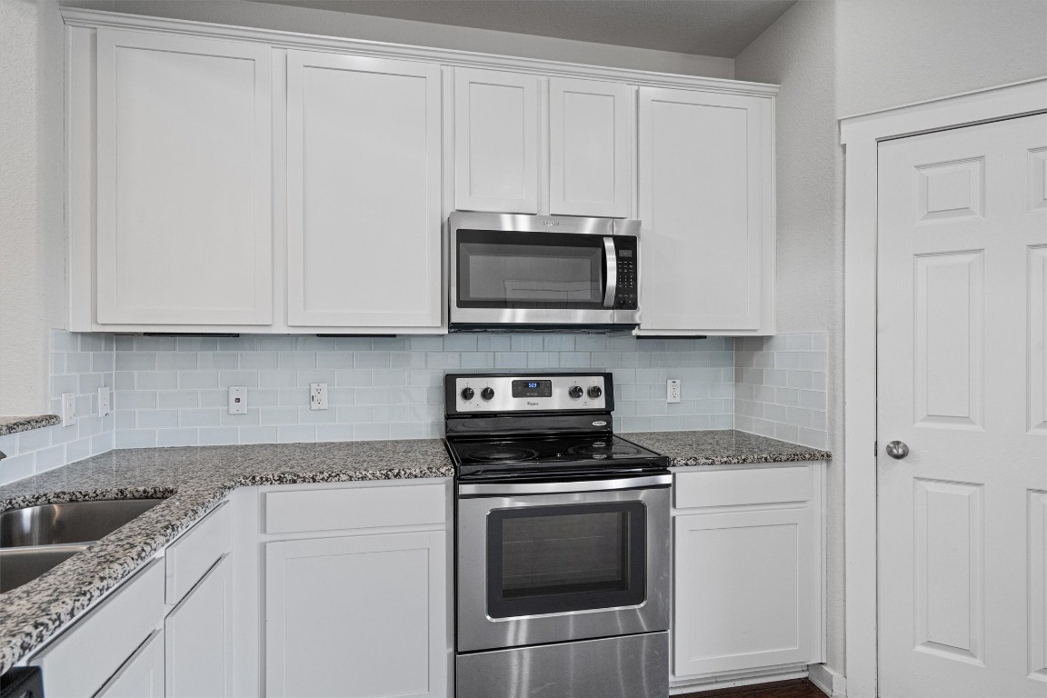 16304 Travesia Way Austin, TX 78728 - Photo 12 of 33 a kitchen with granite countertop white cabinets and stainless steel appliances