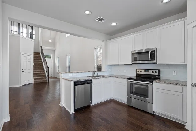 a kitchen with granite countertop white cabinets and stainless steel appliances