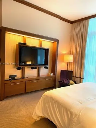 a bedroom with a bed and a flat tv screen on dresser