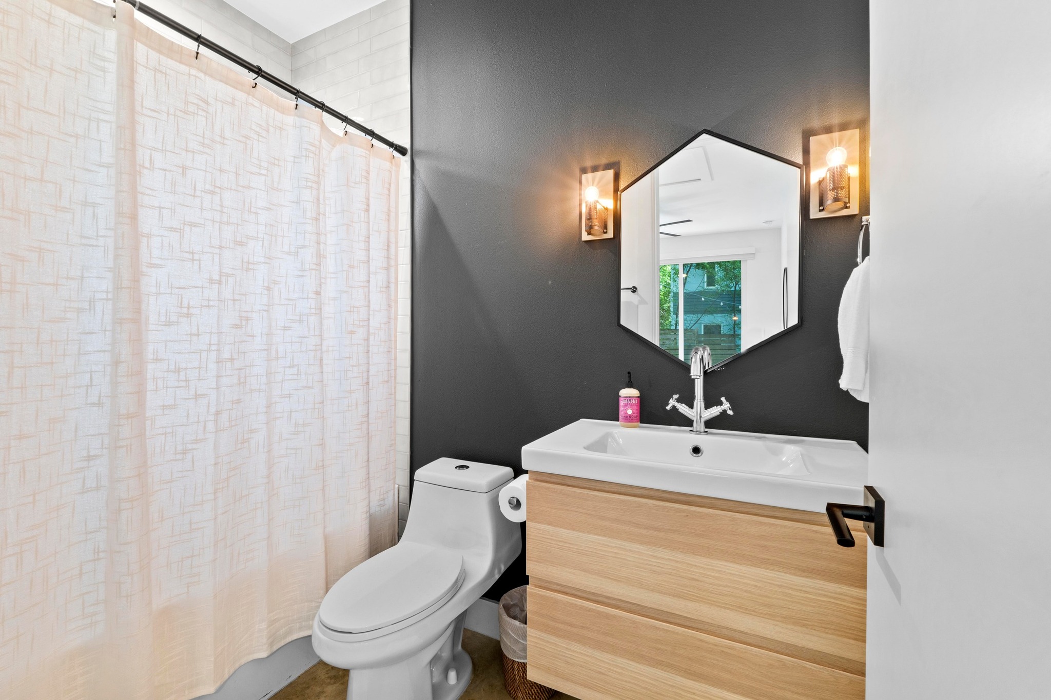 1706 Perez Street, Unit 2 Austin, TX 78721 - Photo 16 of 29 A well-appointed bathroom features a modern vanity with a stylish hexagonal mirror.