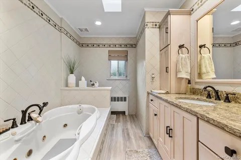 a bathroom with a granite countertop sink mirror and bathtub