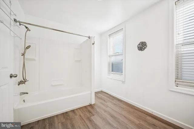 a bathroom with a bathtub a shower and a window