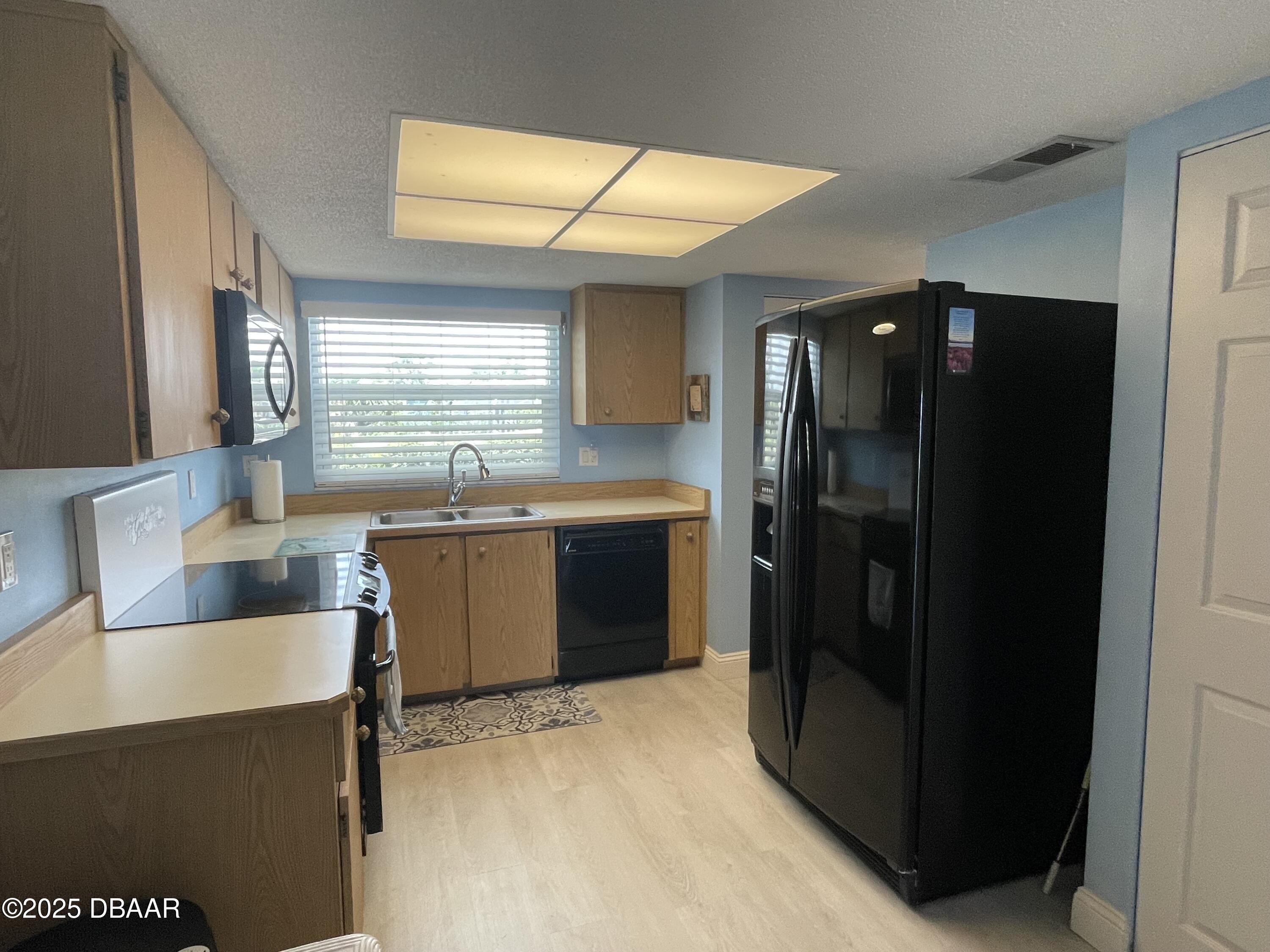 3390 Ocean Shore Boulevard, Unit 101 Ormond Beach, FL 32176 - Photo 12 of 33 a kitchen with granite countertop a refrigerator and a sink