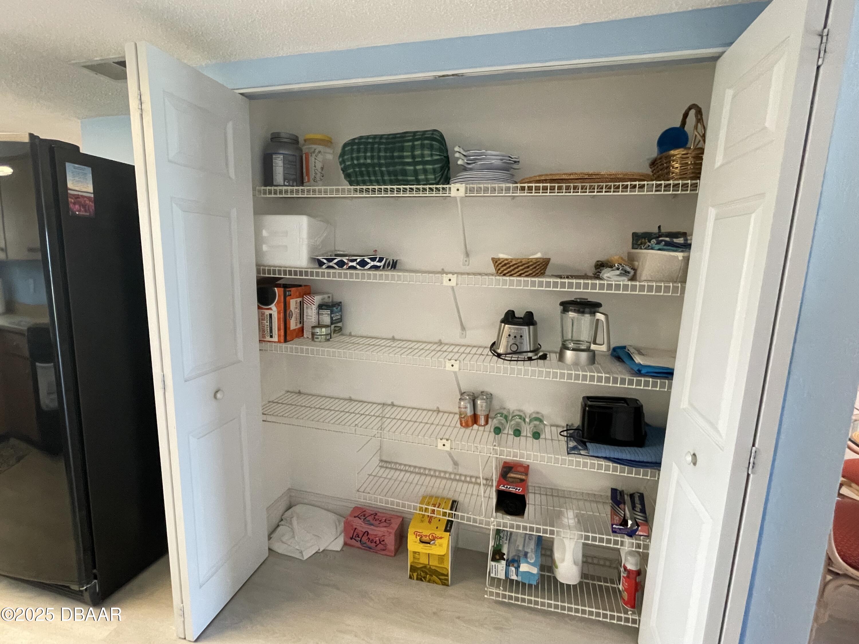 3390 Ocean Shore Boulevard, Unit 101 Ormond Beach, FL 32176 - Photo 13 of 33 a kitchen with a refrigerator and white cabinets