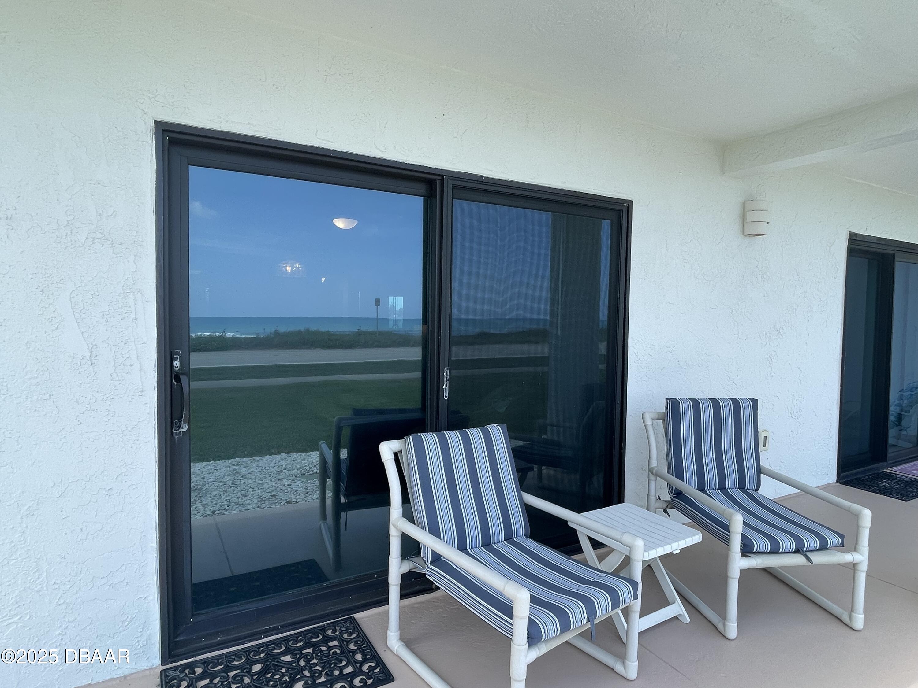 3390 Ocean Shore Boulevard, Unit 101 Ormond Beach, FL 32176 - Photo 25 of 33 a balcony with chairs and a table in a room