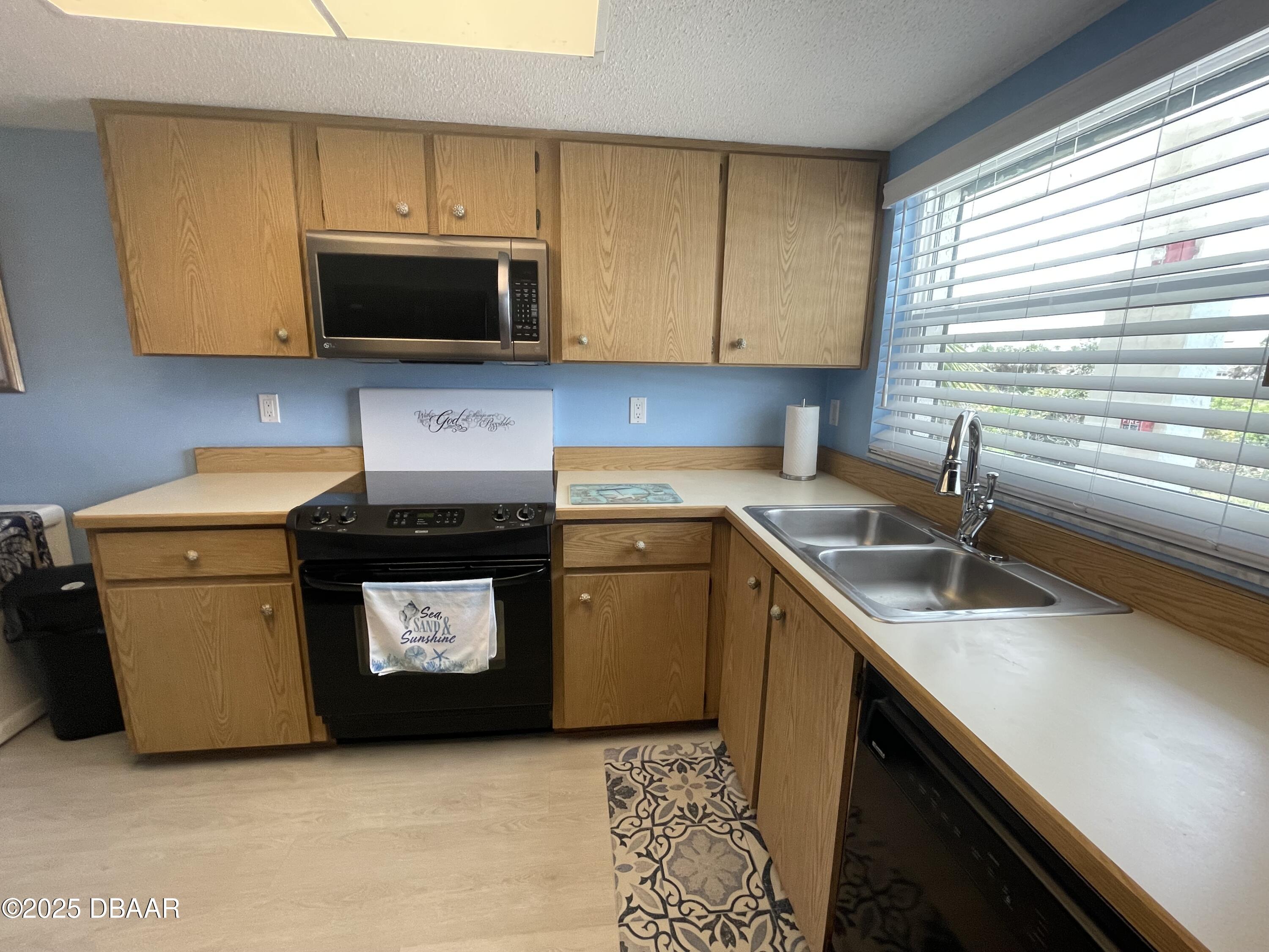 3390 Ocean Shore Boulevard, Unit 101 Ormond Beach, FL 32176 - Photo 10 of 33 a kitchen with stainless steel appliances a sink a stove a microwave a sink and cabinets