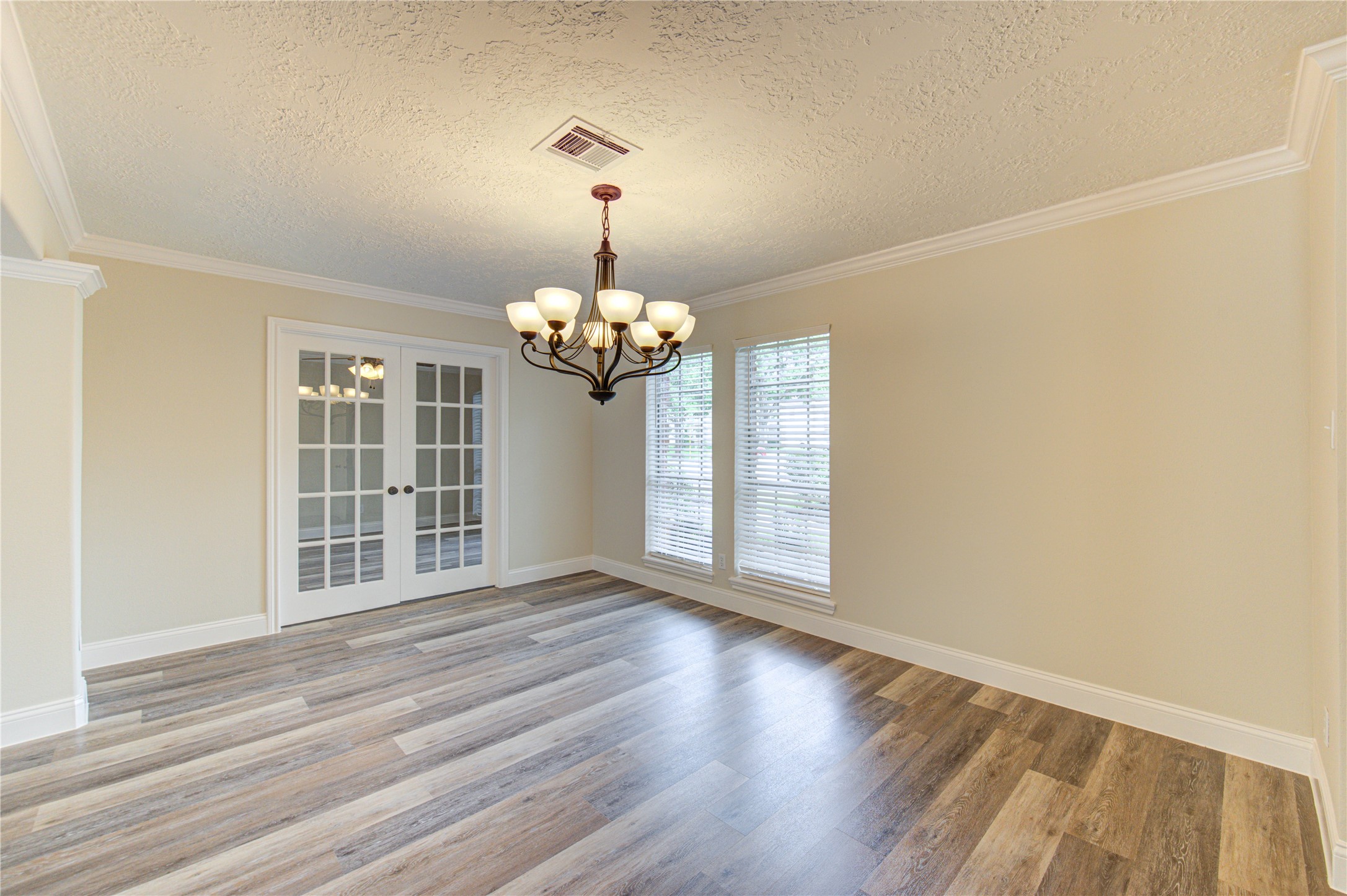 9115 Taidswood Drive Spring, TX 77379 - Photo 5 of 41 The formal dining room displays a vintage chandelier, new and beautiful floors, crown molding, high baseboards, and window blinds. Beyond the French doors is a private home office/study.