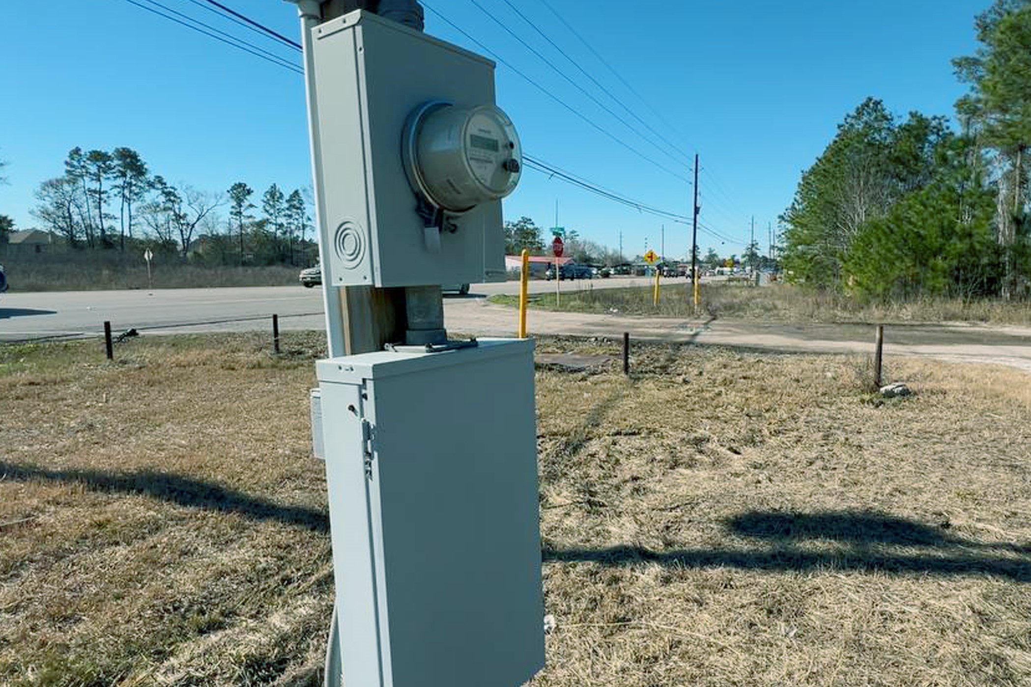 4855 Atascocita Road Humble, TX 77346 - Photo 6 of 6 The photo shows a utility meter and electrical box situated on a grassy roadside area, with nearby trees and a two-lane road in the background. This indicates potential utility access and proximity to main roads.