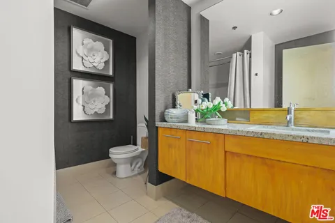 a bathroom with a granite countertop sink and a toilet