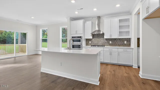 a kitchen with stainless steel appliances granite countertop a stove a sink and white cabinets with wooden floor