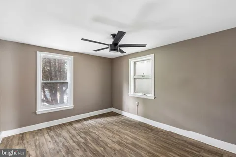 a view of an empty room with window and wooden floor