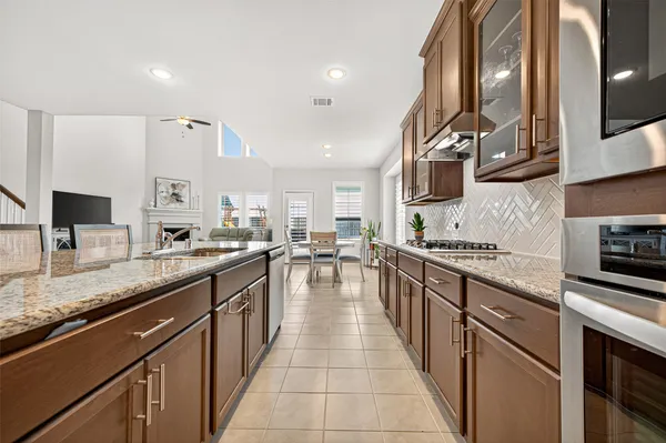 a kitchen with stainless steel appliances a stove a sink a refrigerator white cabinets a dining table and chairs