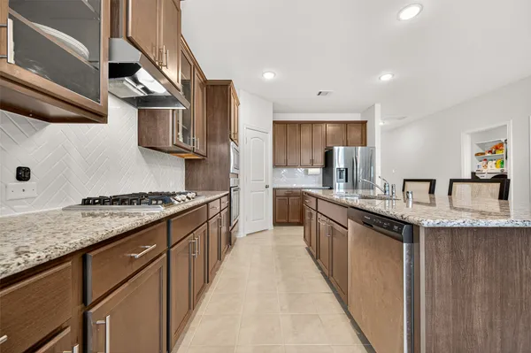 a kitchen with stainless steel appliances a table and chairs in it