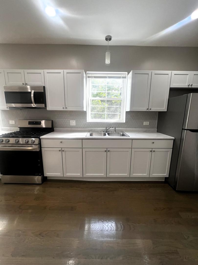 3257 West Warren Boulevard, Unit 2 Chicago, IL 60624 - Photo 19 of 21 a kitchen with stainless steel appliances a sink a stove a microwave a sink and cabinets
