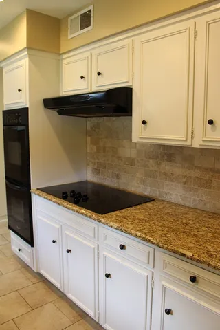 a kitchen with granite countertop white cabinets and white appliances