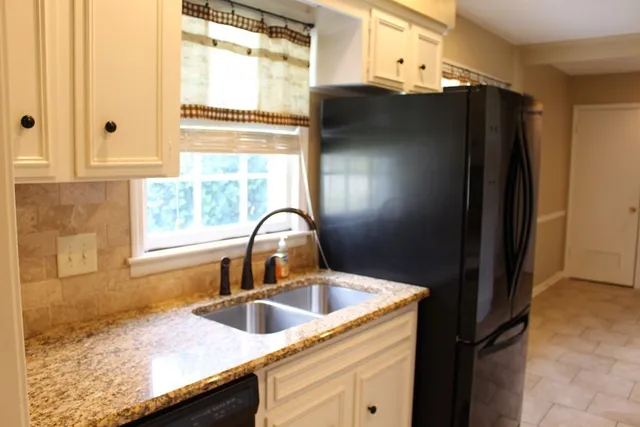a kitchen with granite countertop a refrigerator and a sink