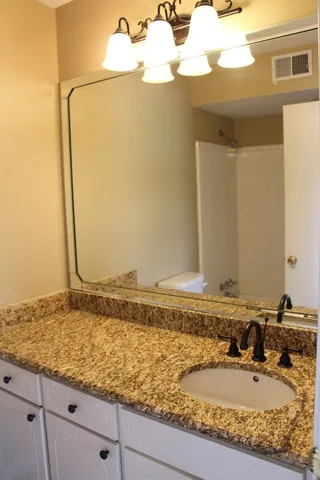 a bathroom with a granite countertop sink and a mirror