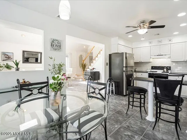 a kitchen with stainless steel appliances kitchen island granite countertop a refrigerator a stove a microwave oven with a dining table and chairs