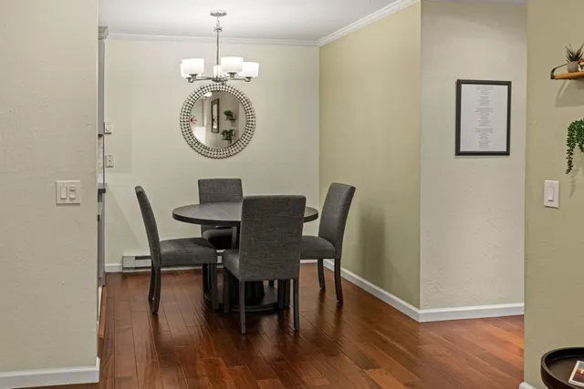 a dining room with wooden floor a glass table and chairs