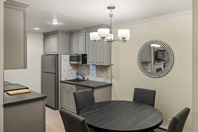 a kitchen with stainless steel appliances granite countertop a dining table chairs refrigerator and microwave